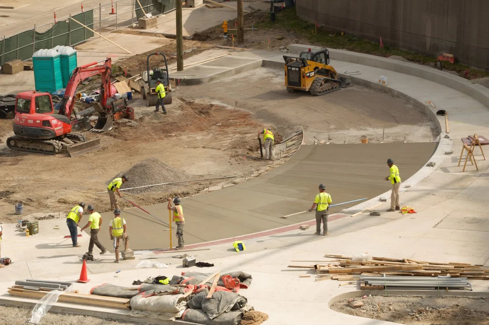 A crew in safety vests finishing a poured concrete slab