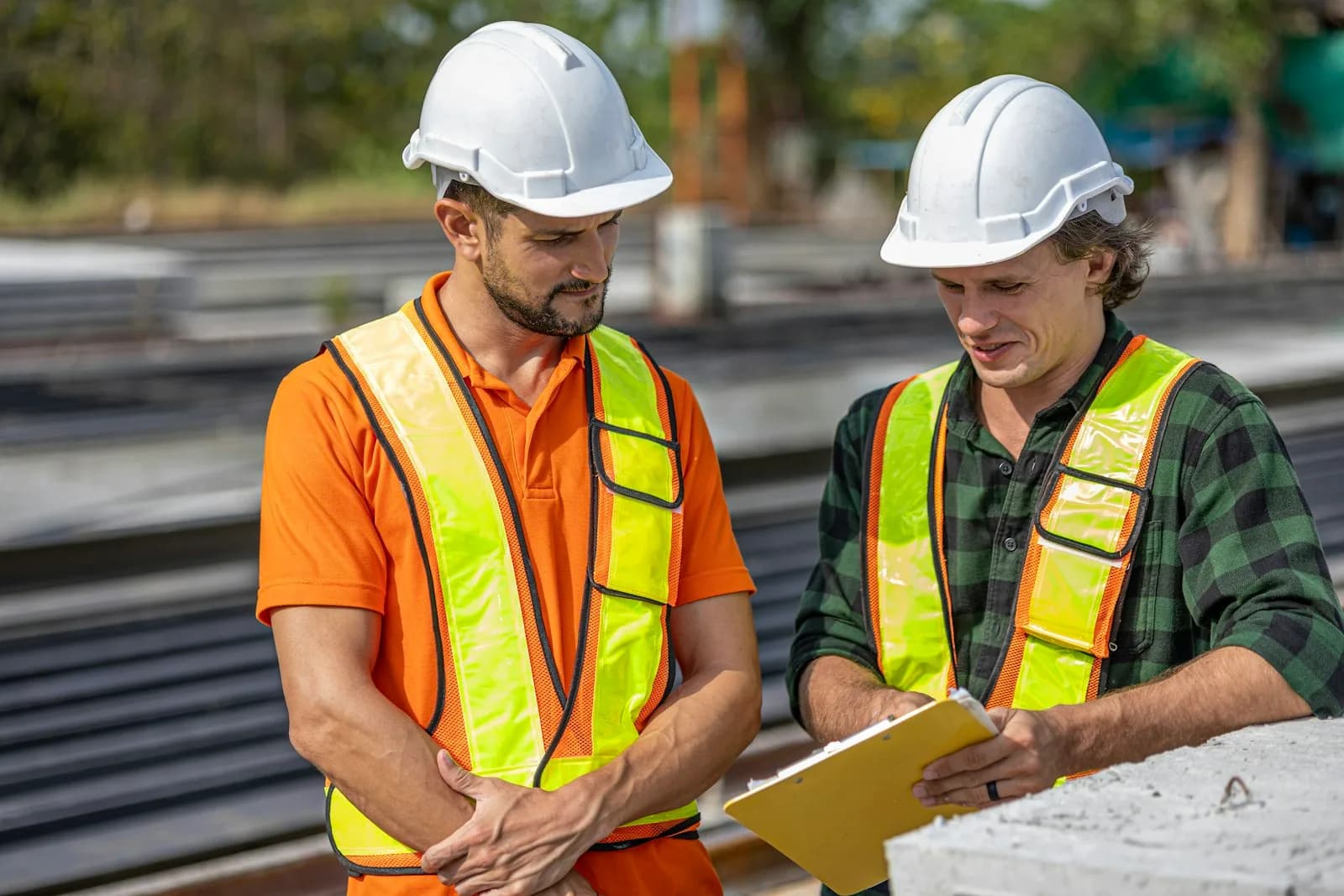 A foreman in a hard hat reviewing plans on a paving site