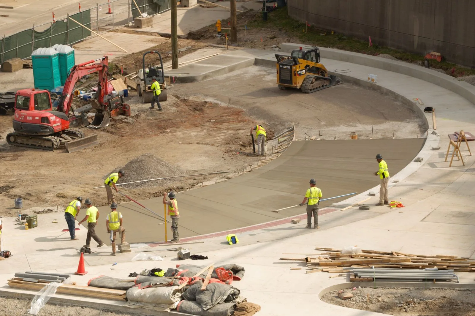 A crew in safety vests finishing a poured concrete slab