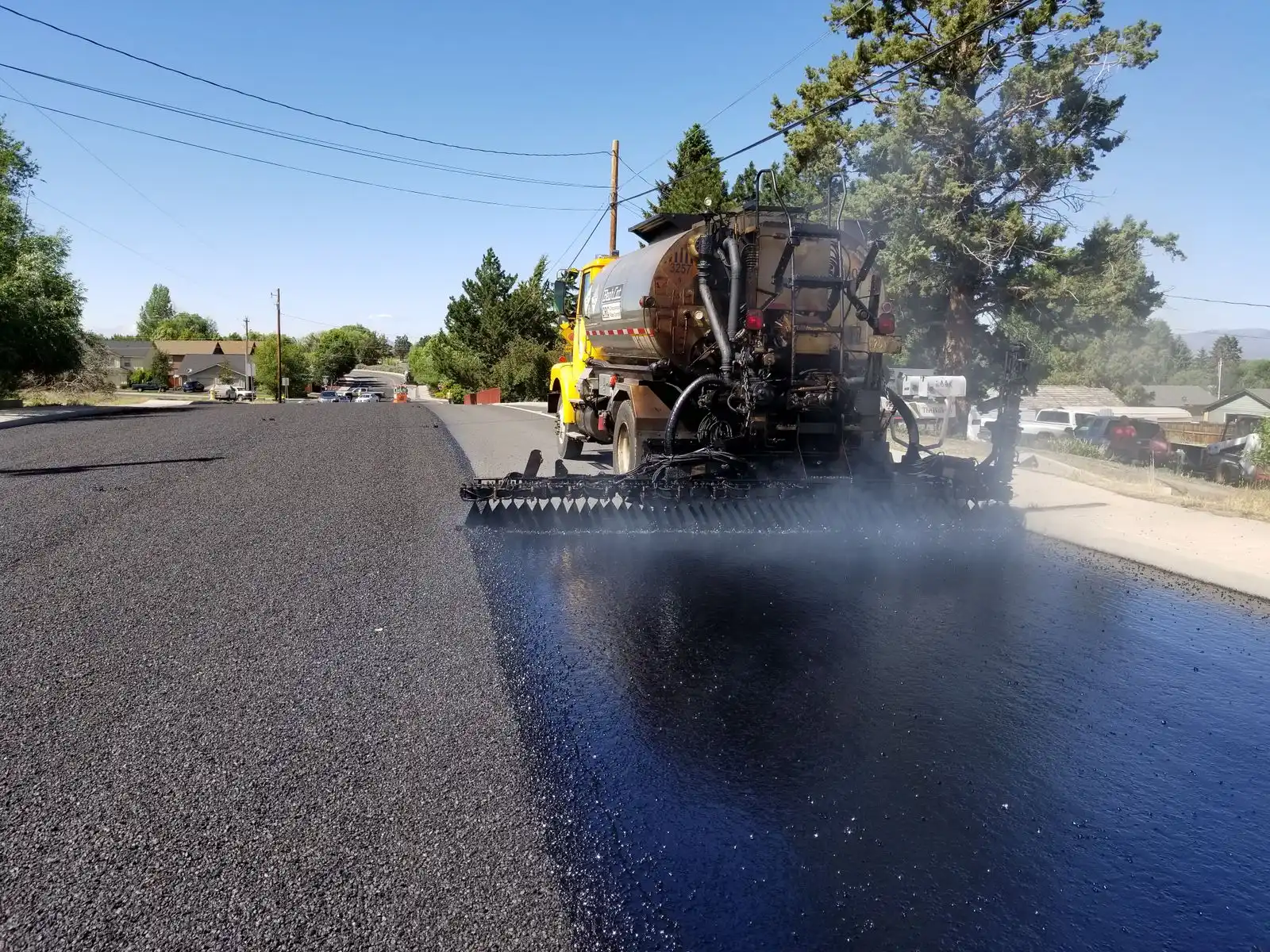 An asphalt paver laying a fresh mat of hot mix behind a distributor truck